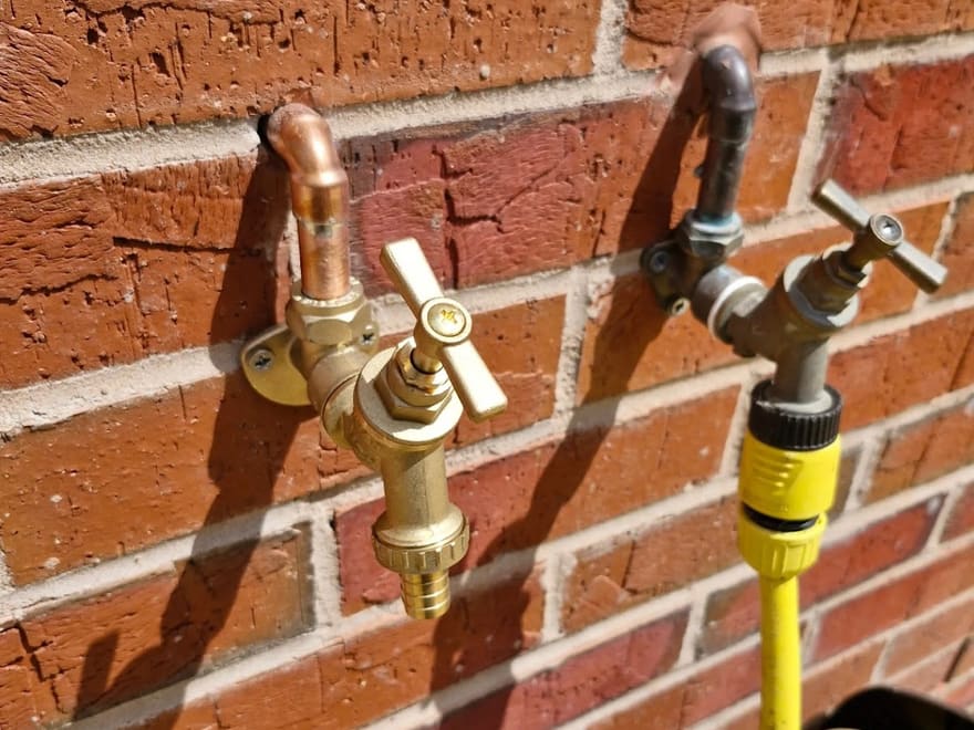 New brass outdoor tap fitted to a brick wall by Lloyd, old tap alongside