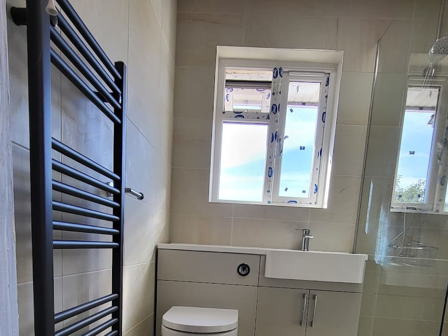 Full bathroom refit by Lloyd with black towel radiator, vanity unit and walk-in shower